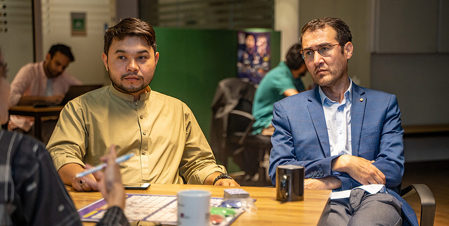 Neimat and Sajjad discussing their work at a desk.