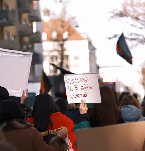 A person holding a sign that reads "we stand with Afghan women"