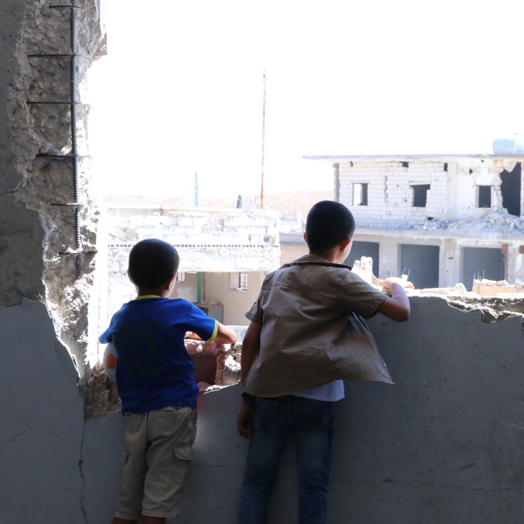 2 children looking out of a bombed building